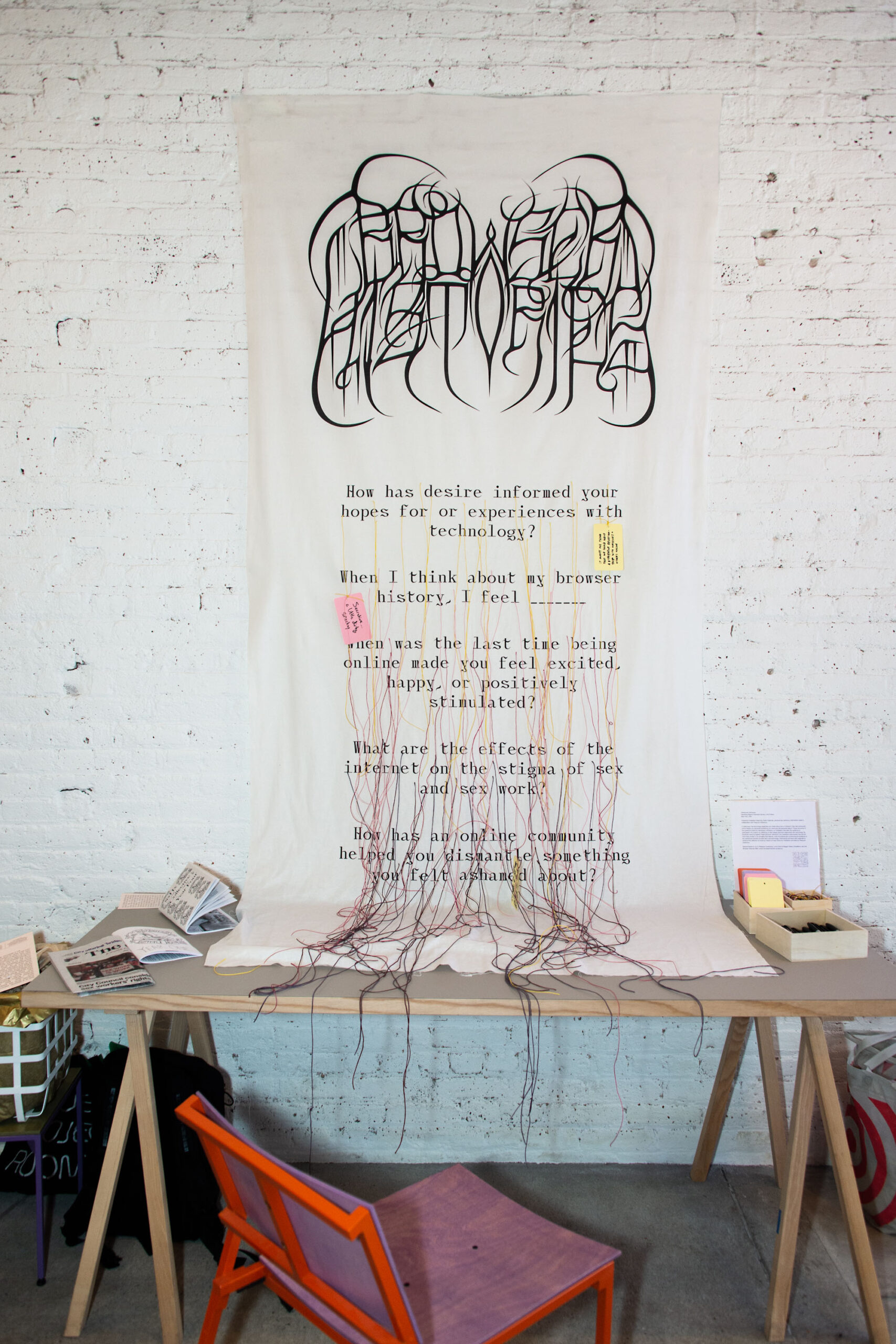 In a gallery installation, a cloth banner printed with a logo spelling 