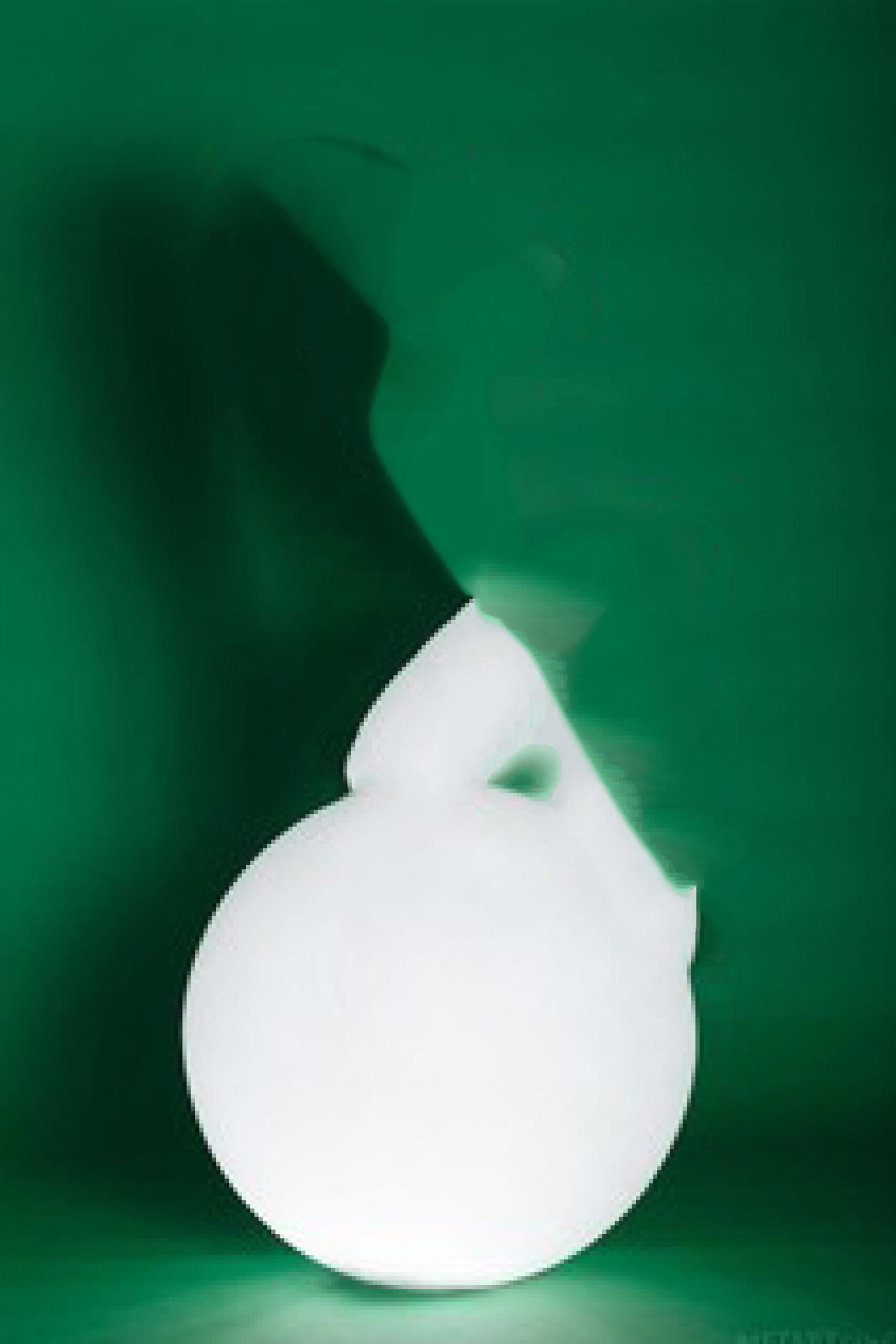 A glowing white orb rests theatrically against a deep green backdrop whose edges are indeterminately blurred.